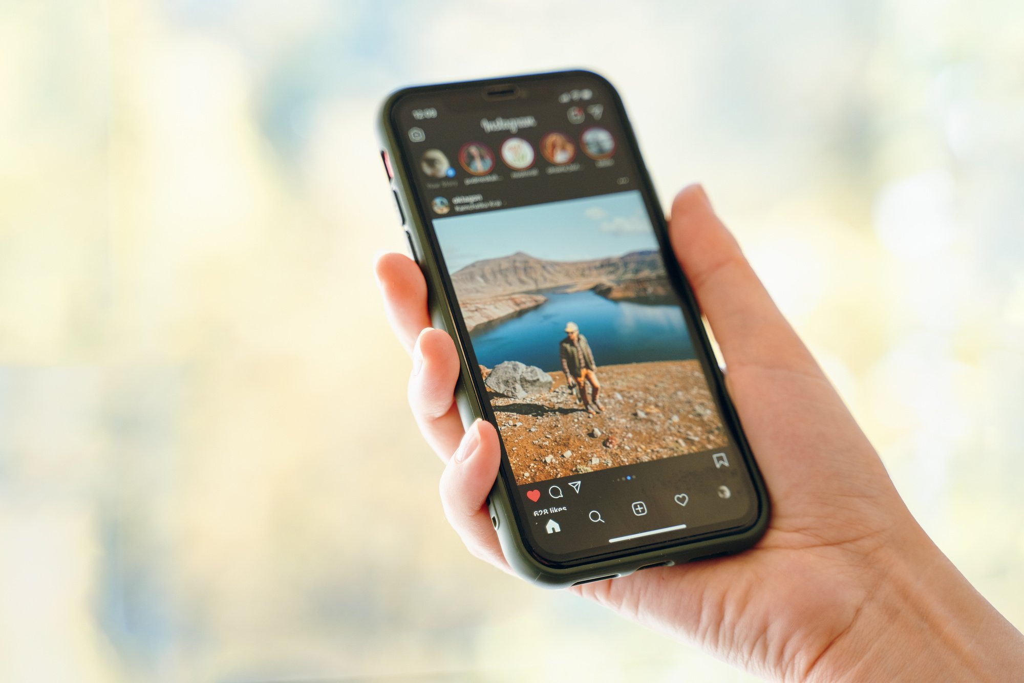 Hand Holding a Smartphone Displaying a Social App Closeup